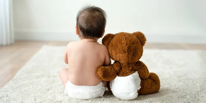 Baby sitting with teddy bear on the floor